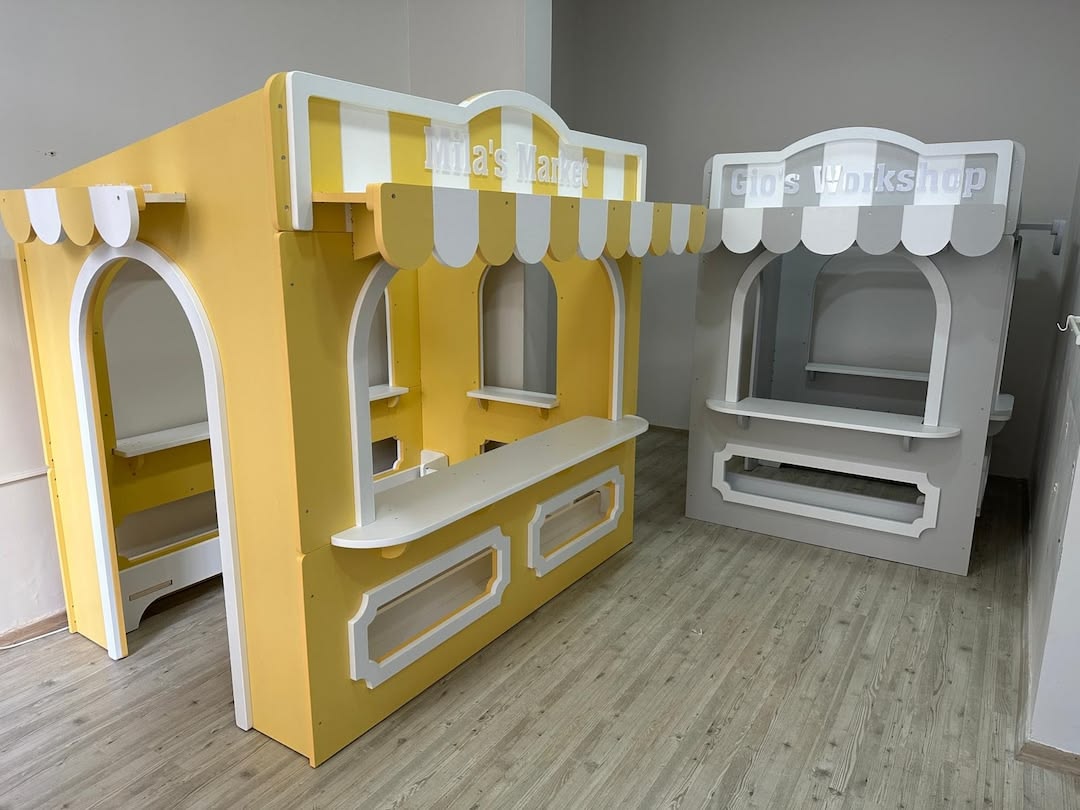 Yellow market playhouse next to a white workshop playhouse